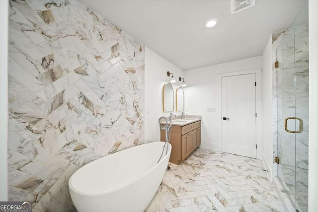 bathroom with vanity, shower with separate bathtub, and tile walls