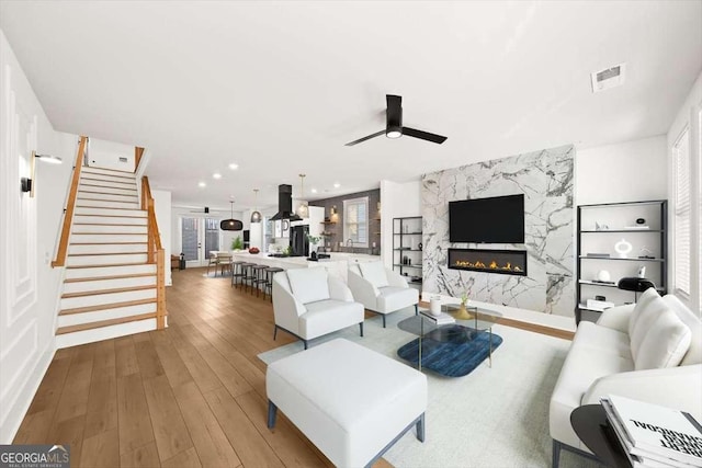 living room with ceiling fan, a high end fireplace, and hardwood / wood-style floors