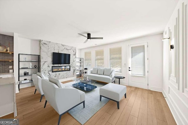 living room with ceiling fan, a fireplace, and light wood-type flooring