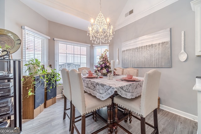 dining room featuring lofted ceiling, light wood-type flooring, and a chandelier