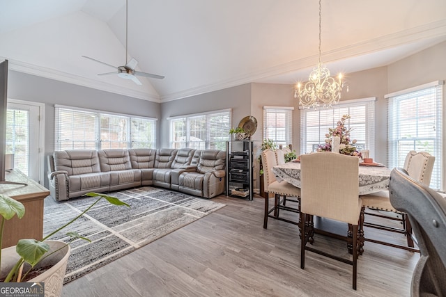 dining room with ceiling fan with notable chandelier, wood-type flooring, and vaulted ceiling