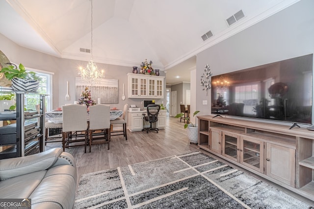 living room featuring hardwood / wood-style floors, an inviting chandelier, vaulted ceiling, and crown molding