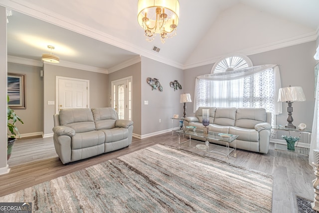 living room featuring hardwood / wood-style floors, a chandelier, lofted ceiling, and ornamental molding