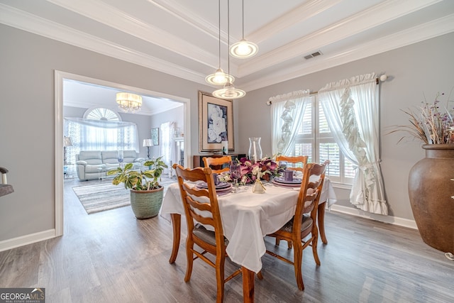 dining room featuring hardwood / wood-style floors, a raised ceiling, crown molding, and a notable chandelier