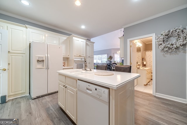 kitchen with light wood-type flooring, white appliances, white cabinetry, and a kitchen island with sink