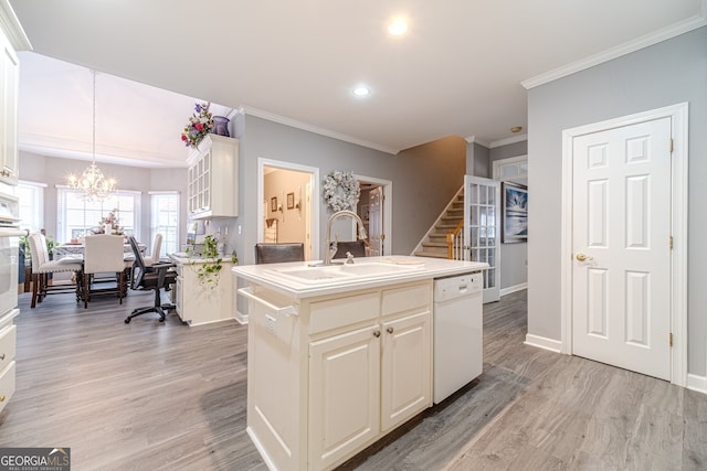 kitchen with sink, hanging light fixtures, light hardwood / wood-style flooring, white dishwasher, and a center island with sink