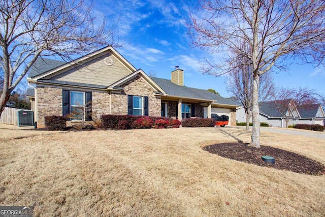 view of front facade with driveway, an attached garage, a front yard, brick siding, and a chimney