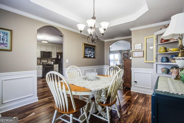 dining space with arched walkways, a raised ceiling, and dark wood-style flooring