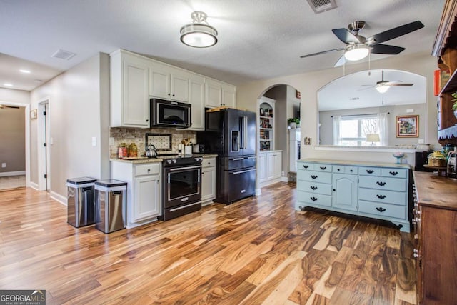 kitchen with white cabinetry, light hardwood / wood-style floors, decorative backsplash, and black appliances