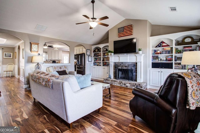 living room with dark hardwood / wood-style floors, a fireplace, lofted ceiling, ceiling fan, and built in shelves