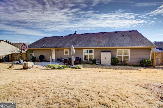 back of property featuring a patio area, a shingled roof, a yard, and fence