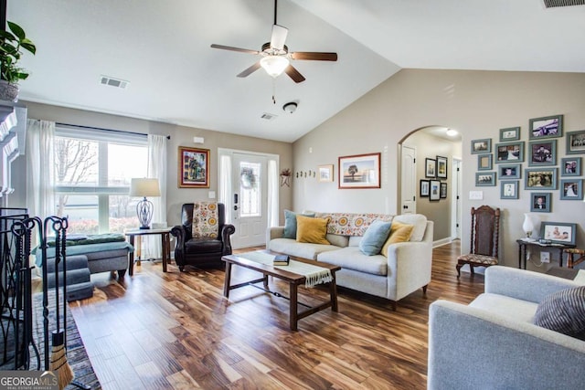 living area featuring arched walkways, visible vents, a ceiling fan, and wood finished floors