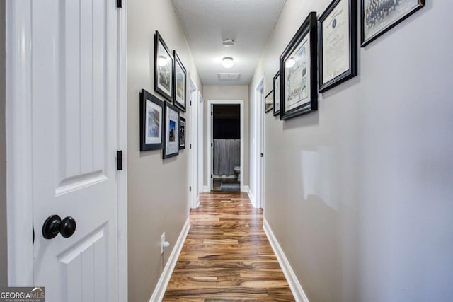 corridor with wood-type flooring and a textured ceiling