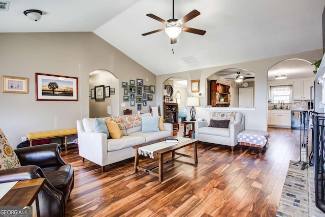 living room with wood finished floors, visible vents, arched walkways, ceiling fan, and vaulted ceiling