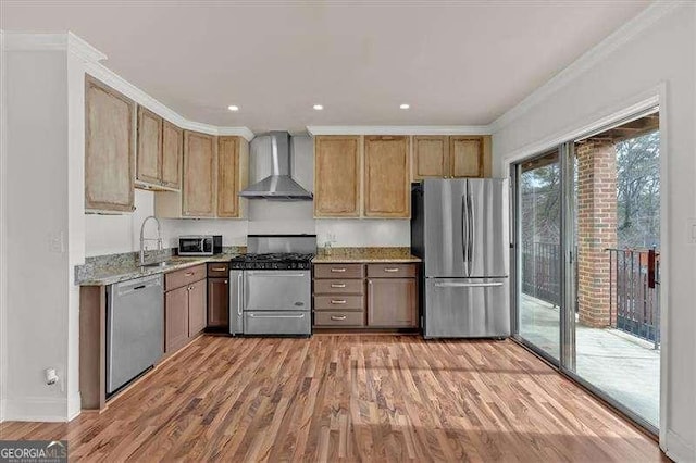 kitchen featuring wall chimney exhaust hood, light stone countertops, ornamental molding, light hardwood / wood-style floors, and stainless steel appliances