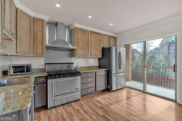 kitchen featuring light stone counters, wall chimney range hood, stainless steel appliances, and ornamental molding