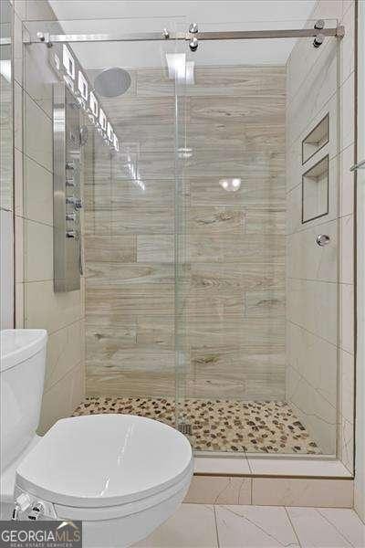 bathroom with a shower with door and toilet