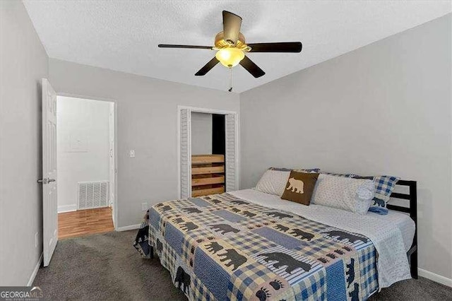 bedroom featuring ceiling fan, a textured ceiling, and dark colored carpet