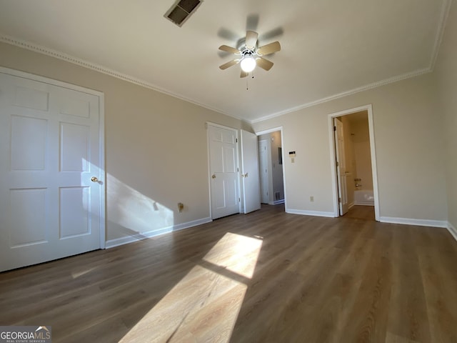 unfurnished bedroom featuring ensuite bathroom, ceiling fan, ornamental molding, and dark wood-type flooring