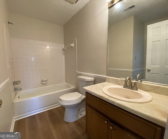 full bathroom with vanity, a textured ceiling, hardwood / wood-style floors, toilet, and tiled shower / bath