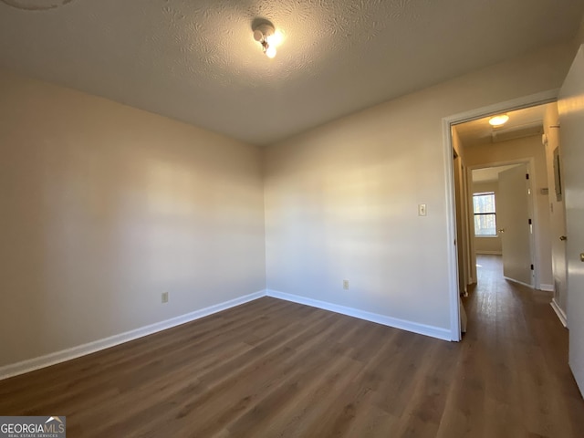 unfurnished room featuring dark hardwood / wood-style flooring and a textured ceiling