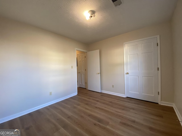 unfurnished bedroom with dark hardwood / wood-style flooring and a textured ceiling