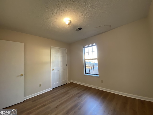 unfurnished bedroom featuring a textured ceiling and dark wood-type flooring