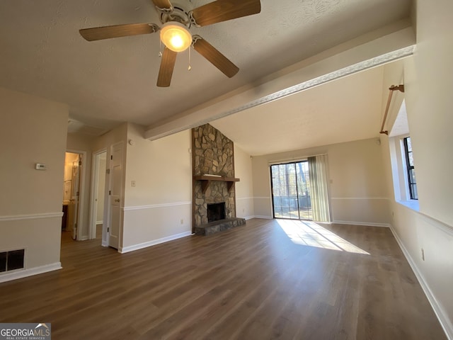 unfurnished living room featuring a stone fireplace, vaulted ceiling with beams, dark hardwood / wood-style floors, ceiling fan, and a textured ceiling