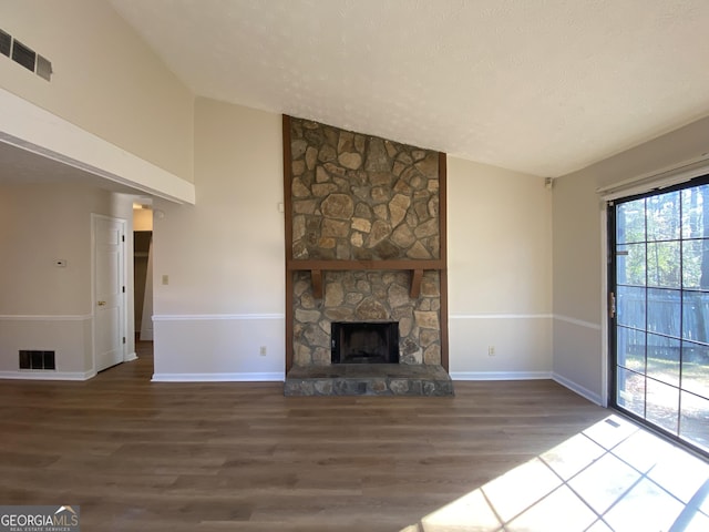 unfurnished living room with hardwood / wood-style floors, lofted ceiling, a fireplace, and a textured ceiling