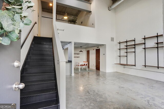 staircase with concrete floors and a towering ceiling