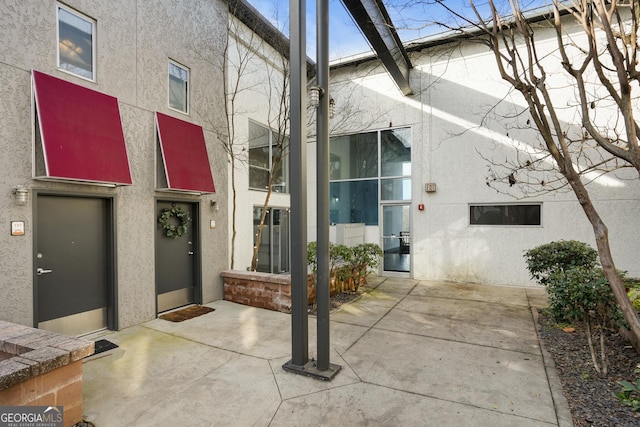 doorway to property featuring a patio area and stucco siding