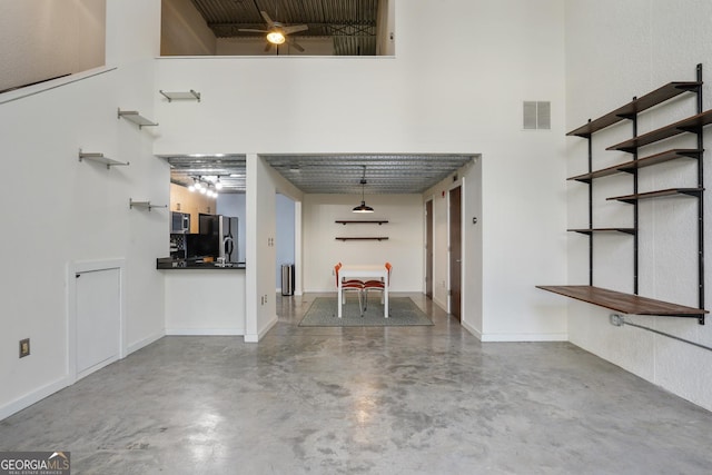 interior space with a towering ceiling, baseboards, finished concrete floors, and visible vents