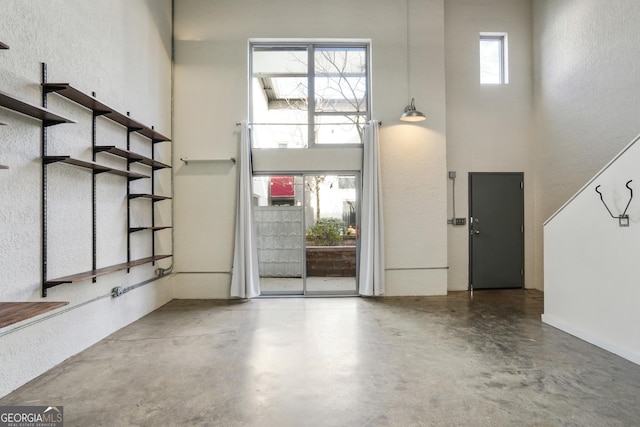 foyer entrance with concrete flooring and a towering ceiling