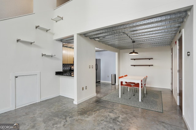 unfurnished dining area with concrete flooring and baseboards