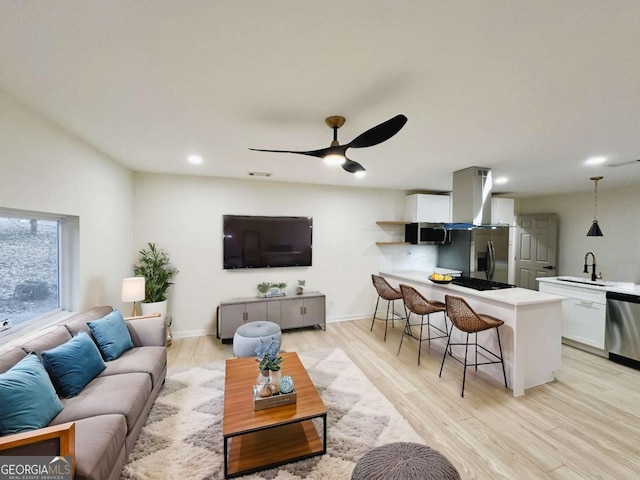 living room featuring sink, ceiling fan, and light hardwood / wood-style floors