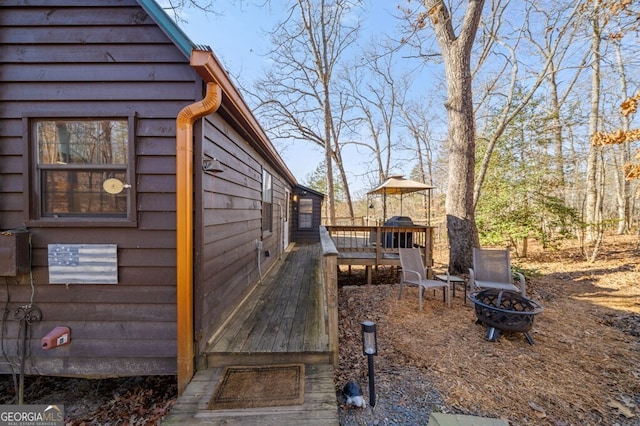 view of property exterior featuring a wooden deck and a fire pit