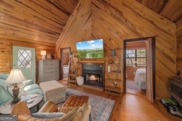 living room with wood walls, light hardwood / wood-style floors, and high vaulted ceiling