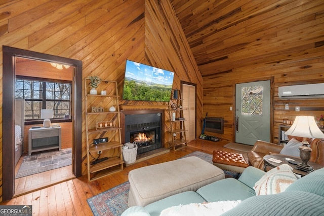 living room with a wall mounted air conditioner, wood walls, wood-type flooring, and high vaulted ceiling