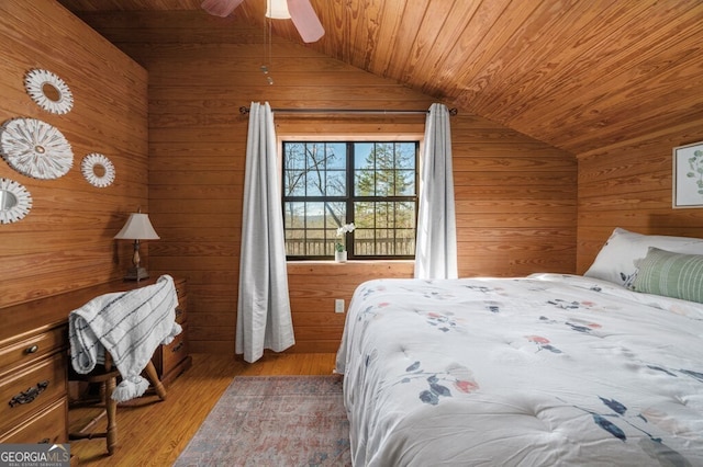 bedroom with vaulted ceiling, ceiling fan, wooden walls, wood-type flooring, and wooden ceiling