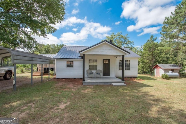 back of house featuring covered porch, a yard, a shed, and a carport