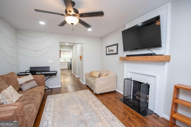 living room with ceiling fan, dark hardwood / wood-style flooring, and a brick fireplace