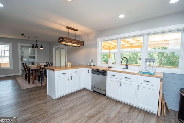 kitchen featuring dishwasher, white cabinets, hanging light fixtures, kitchen peninsula, and washing machine and clothes dryer