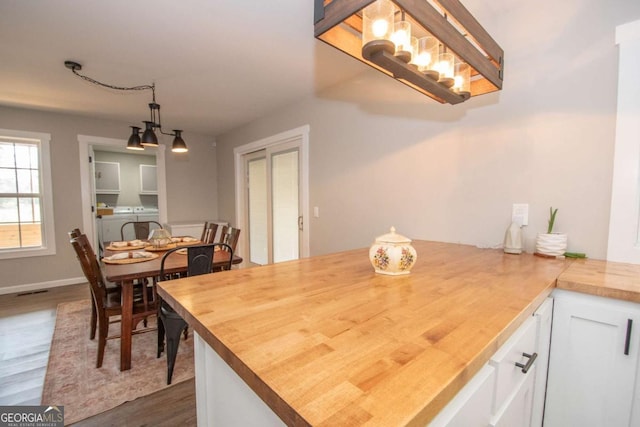 kitchen with white cabinetry, hanging light fixtures, dark hardwood / wood-style floors, and wood counters