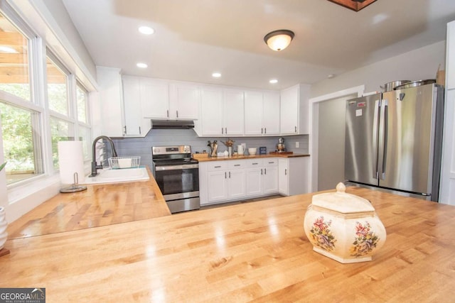 kitchen featuring butcher block counters, sink, stainless steel appliances, tasteful backsplash, and white cabinets