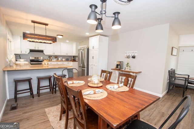 dining space featuring sink, a notable chandelier, and light wood-type flooring