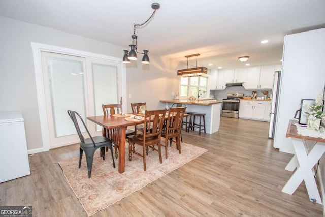 dining space with an inviting chandelier, light hardwood / wood-style flooring, and sink