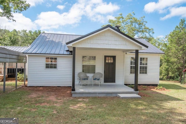 back of house with a carport, covered porch, and a yard