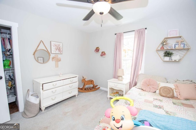 carpeted bedroom featuring a walk in closet, a closet, and ceiling fan