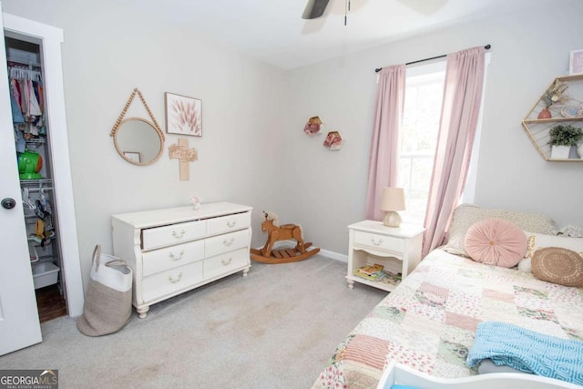 carpeted bedroom with ceiling fan, a walk in closet, and a closet