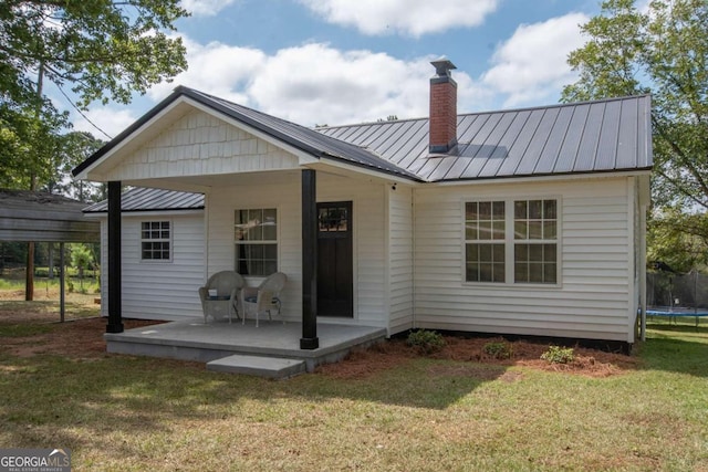 rear view of property featuring a yard and a trampoline